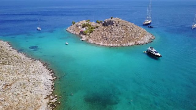 August 2017: Aerial drone video of small heart shaped island with picturesque church of Agia Marina and turquoise clear waters, Symi island, Dodecanese, Aegean, Greece