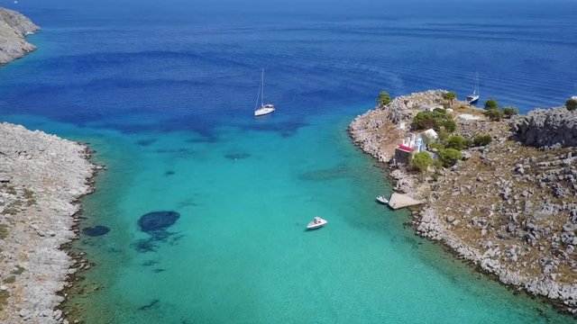 August 2017: Aerial drone video of small heart shaped island with picturesque church of Agia Marina and turquoise clear waters, Symi island, Dodecanese, Aegean, Greece