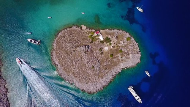 August 2017: Aerial drone video of small heart shaped island with picturesque church of Agia Marina and turquoise clear waters, Symi island, Dodecanese, Aegean, Greece