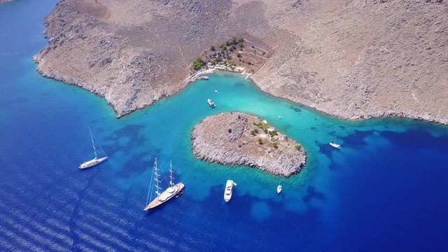 August 2017: Aerial drone video of small heart shaped island with picturesque church of Agia Marina and turquoise clear waters, Symi island, Dodecanese, Aegean, Greece