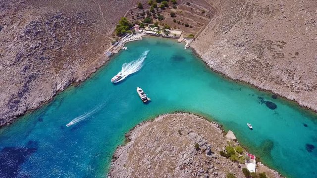 August 2017: Aerial drone video of small heart shaped island with picturesque church of Agia Marina and turquoise clear waters, Symi island, Dodecanese, Aegean, Greece