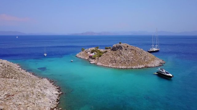 August 2017: Aerial drone video of small heart shaped island with picturesque church of Agia Marina and turquoise clear waters, Symi island, Dodecanese, Aegean, Greece