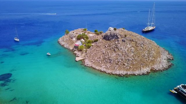 August 2017: Aerial drone video of small heart shaped island with picturesque church of Agia Marina and turquoise clear waters, Symi island, Dodecanese, Aegean, Greece