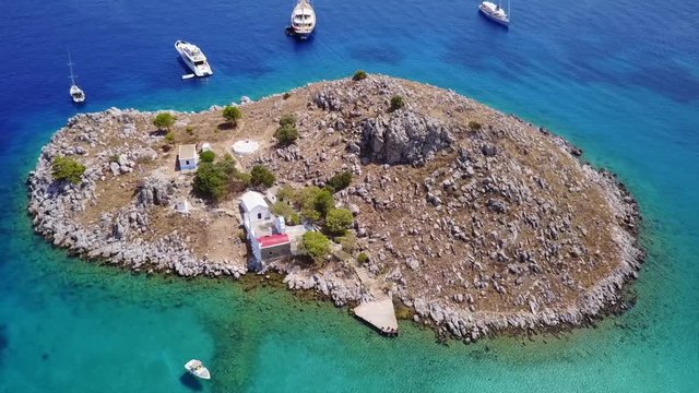 August 2017: Aerial drone video of small heart shaped island with picturesque church of Agia Marina and turquoise clear waters, Symi island, Dodecanese, Aegean, Greece