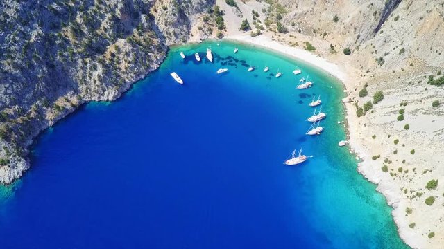 August 2017: Aerial drone video of iconic rocky bay and famous beach of Agios Georgios with turquoise clear waters and boats docked, Symi island, Dodecanese, Aegean, Greece