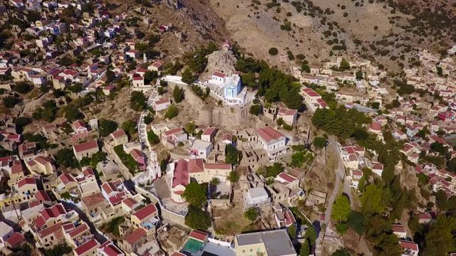 August 2017: Aerial drone video of picturesque castle in Ano chora in island of Symi with traditional architecture and dominant colors, Dodecanese, Aegean, Greece