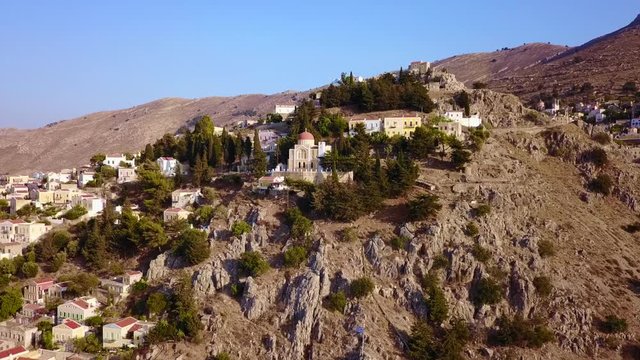 August 2017: Aerial drone video of picturesque castle in Ano chora in island of Symi with traditional architecture and dominant colors, Dodecanese, Aegean, Greece