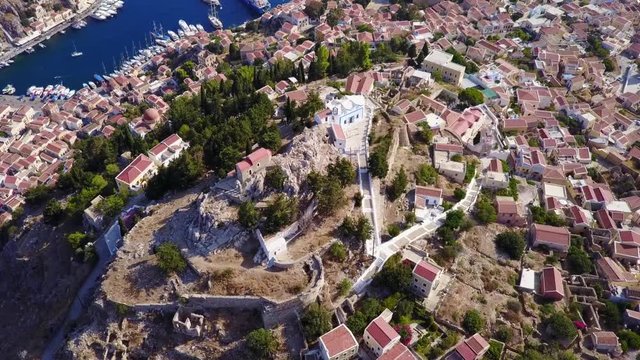 August 2017: Aerial drone video of picturesque castle in Ano chora in island of Symi with traditional architecture and dominant colors, Dodecanese, Aegean, Greece