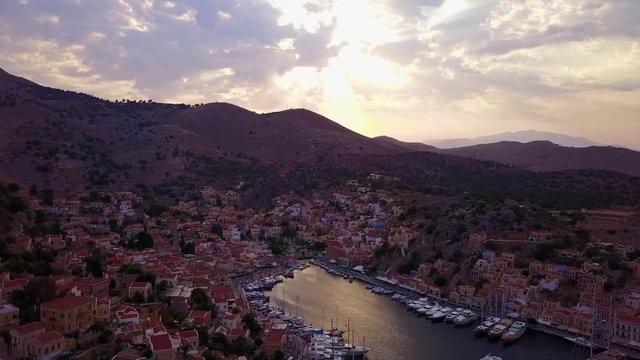 August 2017: Aerial drone video of picturesque island and main port of Symi with traditional architecture and dominant colors at dusk, Dodecanese, Aegean, Greece