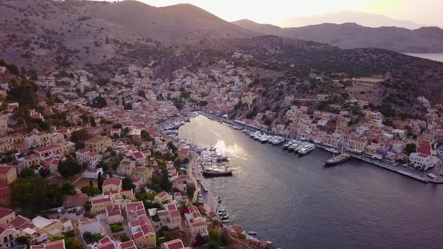 August 2017: Aerial drone video of picturesque island and main port of Symi with traditional architecture and dominant colors at dusk, Dodecanese, Aegean, Greece