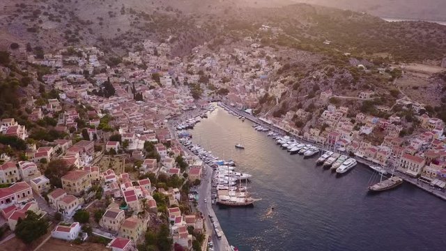 August 2017: Aerial drone video of picturesque island and main port of Symi with traditional architecture and dominant colors at dusk, Dodecanese, Aegean, Greece