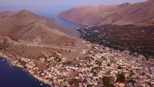 August 2017: Aerial drone video of picturesque island and main port of Symi with traditional architecture and dominant colors at dusk, Dodecanese, Aegean, Greece