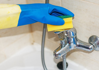 House cleaning. Woman cleaning tap in bathroom.