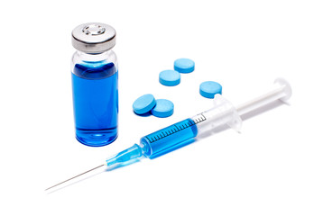 A syringe with blue vaccine and pills