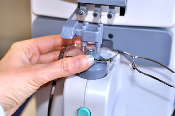 Female optician measuring and preparing glasses on the digital device in optical store 