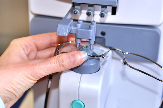 Female optician measuring and preparing glasses on the digital device in optical store 
