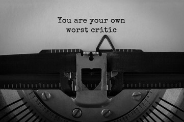 Text You are your own worst critic typed on retro typewriter