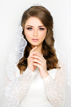 Beautiful spanish style bride with veil and professional make-up. Girl with curls in a wedding image. Close-up, white background.