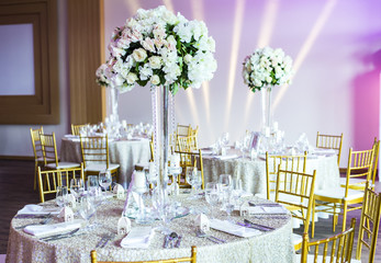 Large vase with beautiful roses stands on rich decorated wedding table
