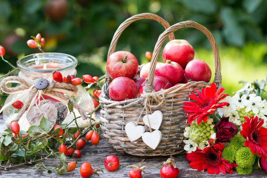 Herbstdekoration mit Äpfel im Weidenkorb,Herbstblumen und Hagebutten als Kartenmotiv