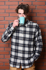 handsome guy holding cup on brick wall background