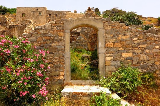 doorway to ruins with wildflowers on Spinalonga Island, Crete, Greece. Decay and rebirth concept