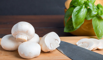 mushrooms sliced on a wooden plank with knife and stone casserole