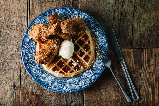 Chicken wings and waffles served with butter and blackberry syrup