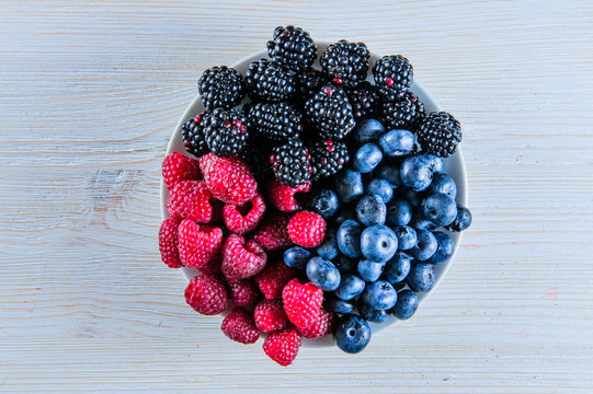 Various fresh summer berries, raspberries and blackberries on white background.