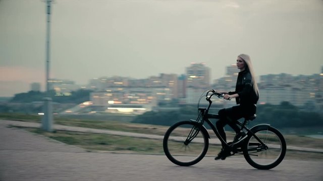 Beautiful woman rides a bicycle near a tall building 4k