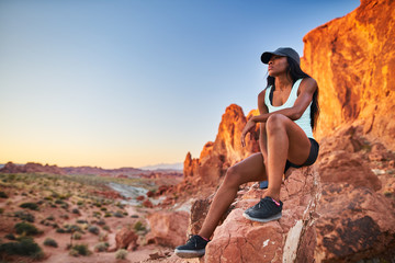 african american woman resting on rock at valley of fire park during hike