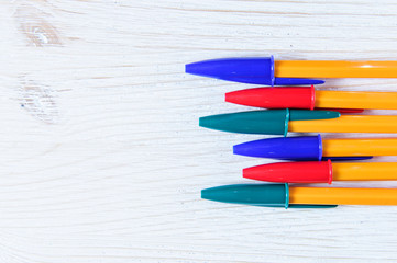 Obraz premium Colorful pens on white wooden background
