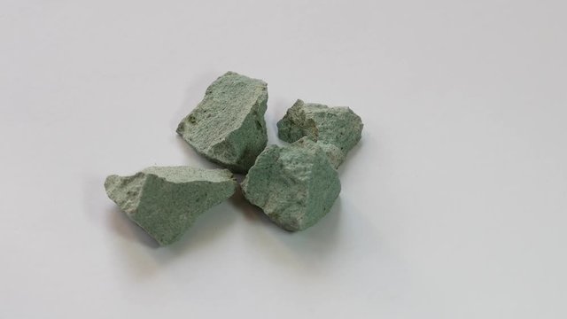 Zeolite natural raw stones rotating on white background.