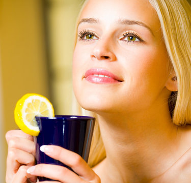 Cheerful blond woman with cup of tea, indoor