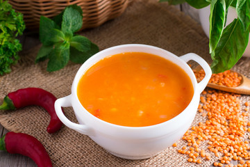 Lentil soup in a ceramic white bowl on a wooden background