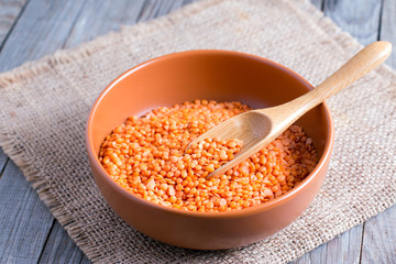 Red lentils in a ceramic bowl on a wooden background