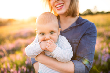 Unrecognizable mother in nature with baby son in the arms.