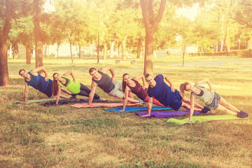 Group of young people training on mats in park