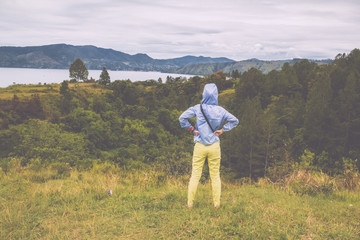 Fototapeta premium woman standing on hill looking at the lake toba