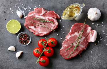 Composition with fresh raw steaks, vegetables and spice on table