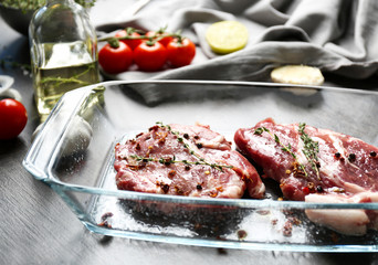 Baking dish with fresh raw steaks on table