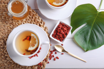 Cup with goji tea on wicker mat