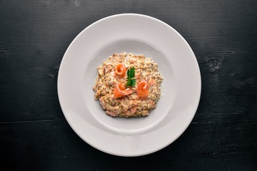 Risotto with salmon and cream sauce. On a wooden background. Top view. Free space.