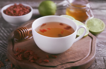 Cup with goji tea on wooden board