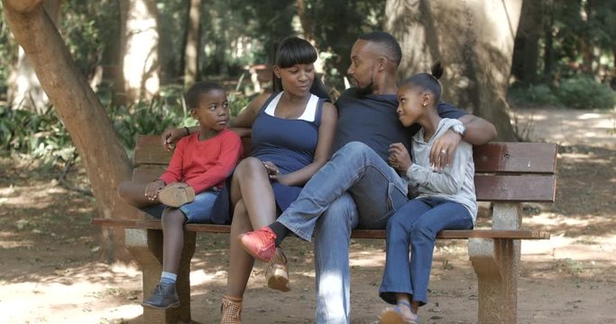  Happy family group relaxing in the park & chatting on a summer day