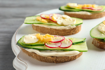 Tasty sandwiches with fresh cucumber on wooden board
