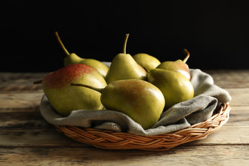 Wicker plate with delicious ripe pears on table