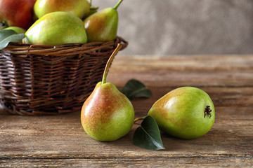 Delicious ripe pears and wicker basket on table