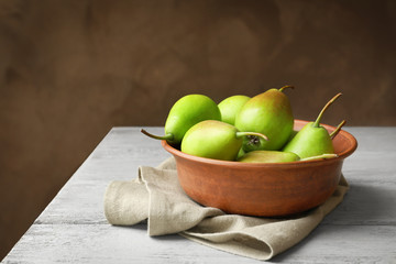 Bowl with delicious ripe pears on table