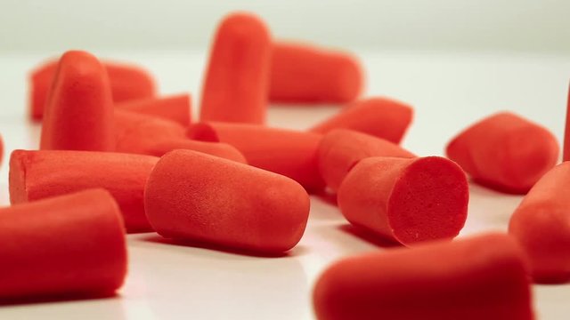 Earplugs offer hearing protection against harmful noise. Red ear plugs on white background, soft polyurethane foam
